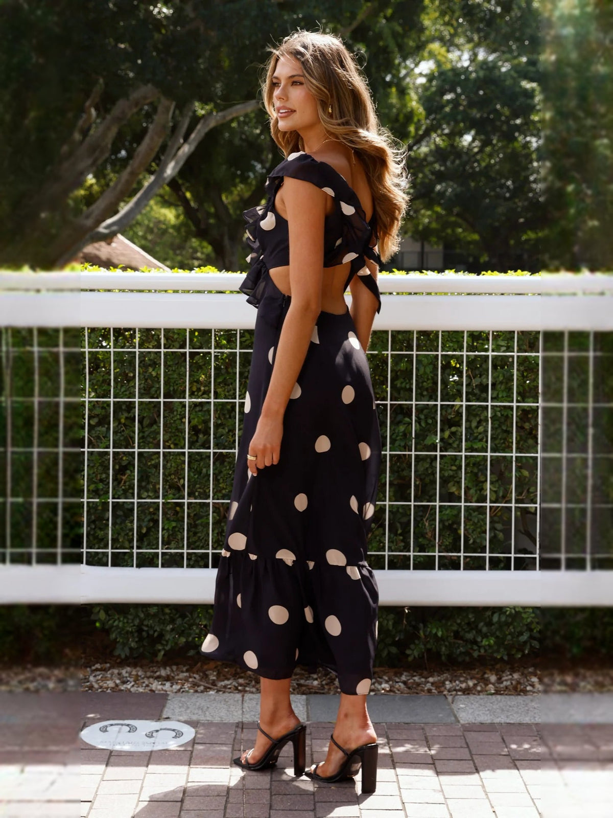 Black polka-dot midi dress with sleeveless ruffle details and tiered skirt
