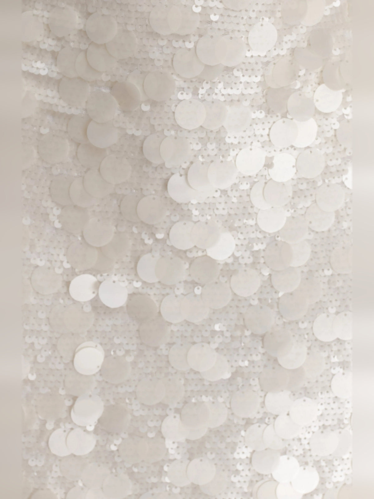 Close-up of ivory sequin fabric with overlapping round sequins