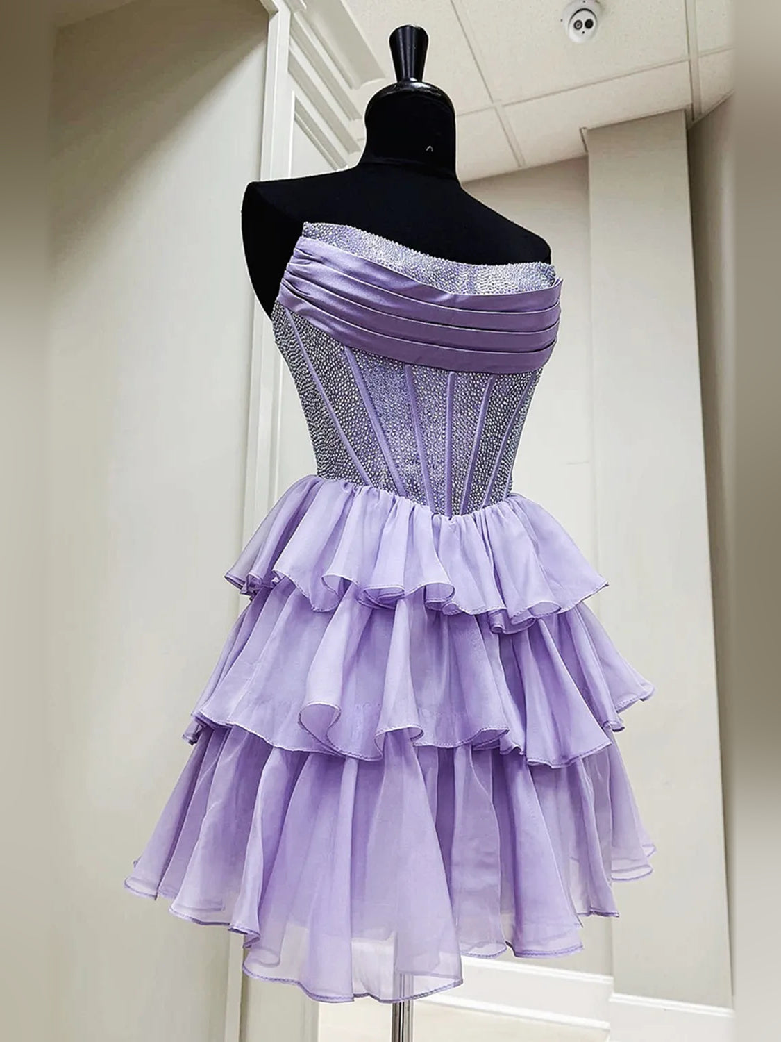 Lilac strapless tiered mini dress on mannequin with ruffle layers and corset bodice