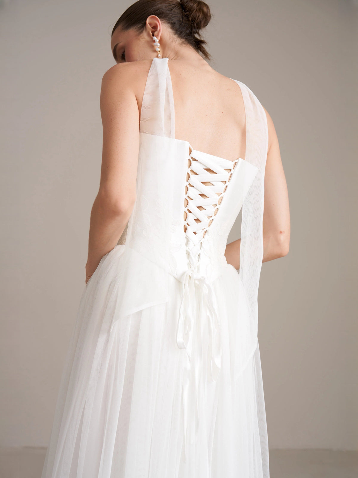Ivory wedding dress back with lace-up corset detail and draped sheer panel