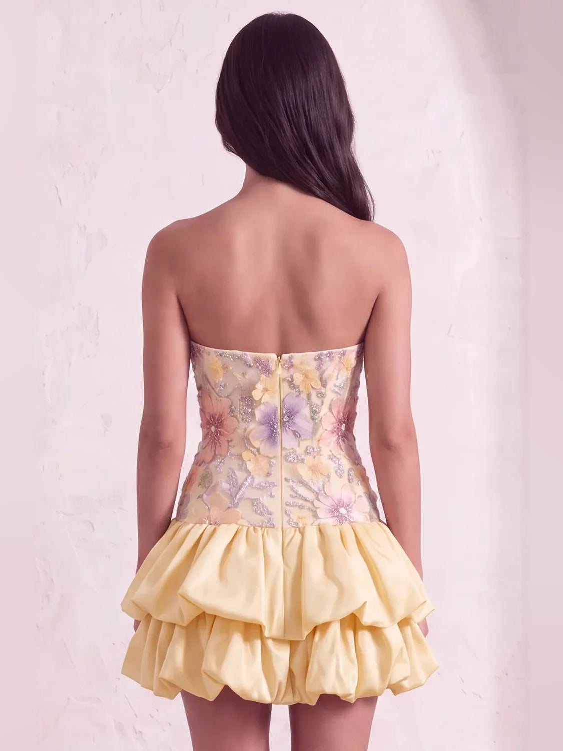 Back view of light yellow strapless mini dress with floral corset bodice and ruffles