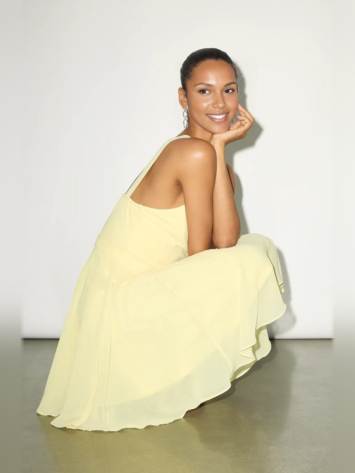 Pale yellow halter neck mini dress with draped skirt and fitted bodice