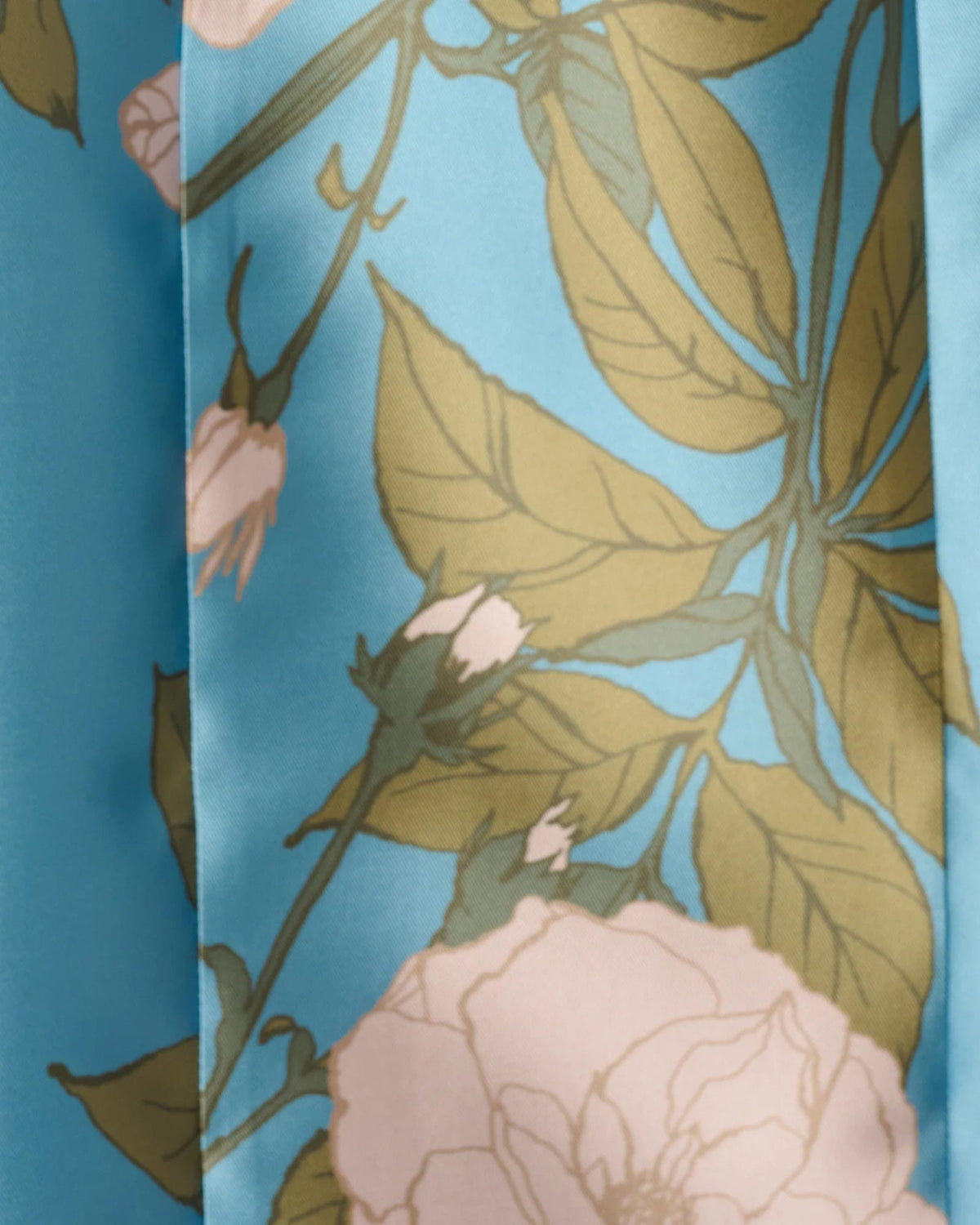 Close-up of blue floral print fabric with green leaves and blush flower shapes