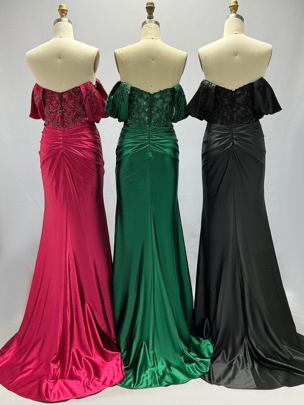 Off-shoulder formal dresses on mannequins in deep red, green, and black, ruched bodice.