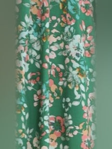 Green floral fabric close-up with small pink and white blossoms