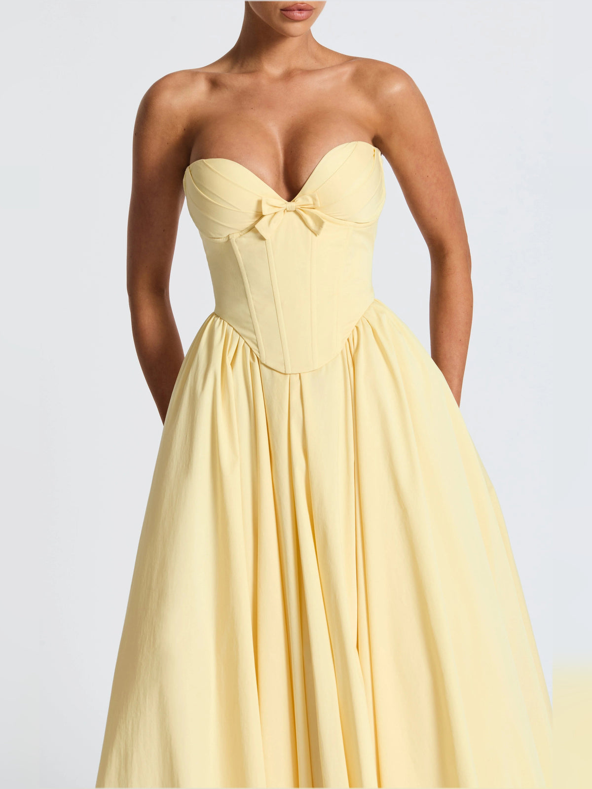 Close-up of lemon yellow strapless sweetheart midi dress bodice with bow and corset fit
