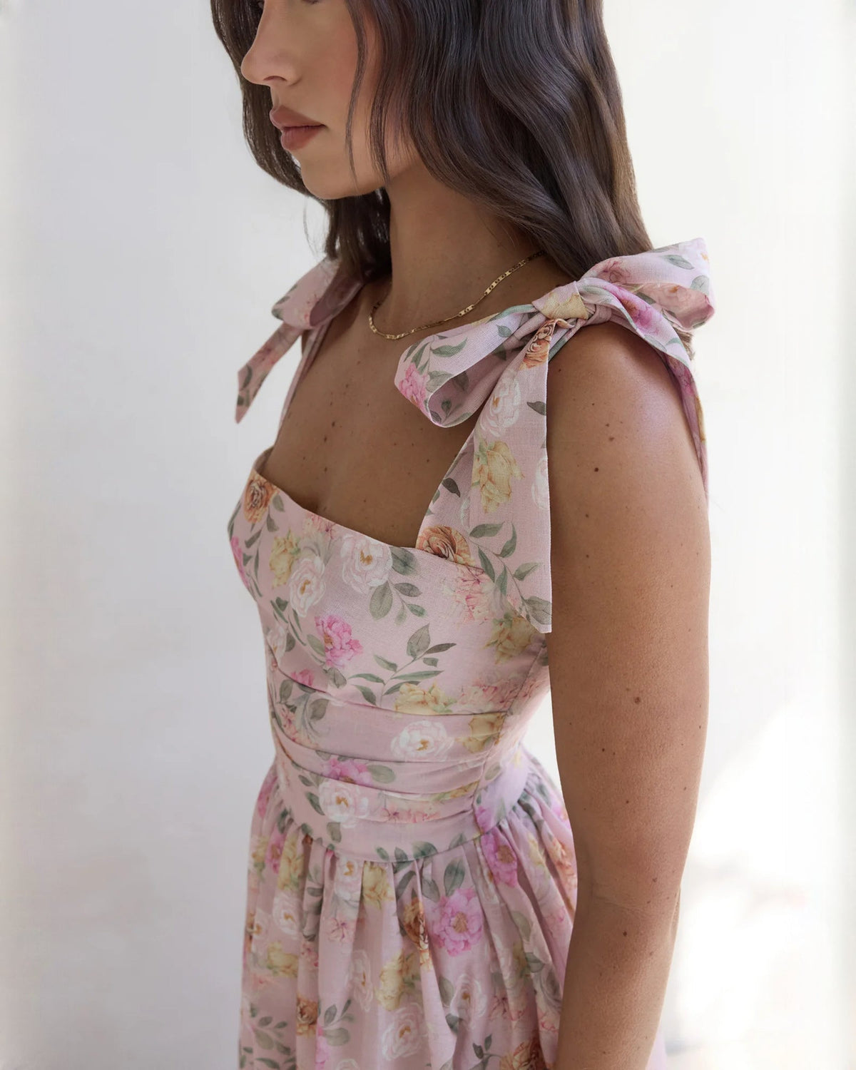 Close-up of pink floral satin bodice with spaghetti straps and bow at shoulder