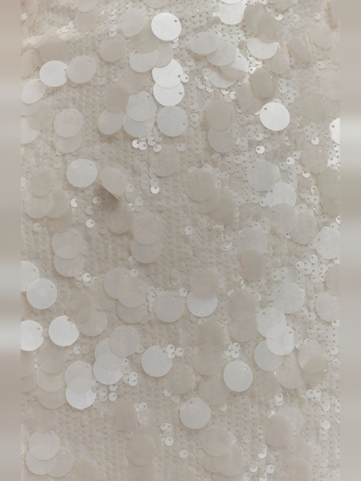 Close-up of ivory sequins on mini dress fabric with circular sequin pattern