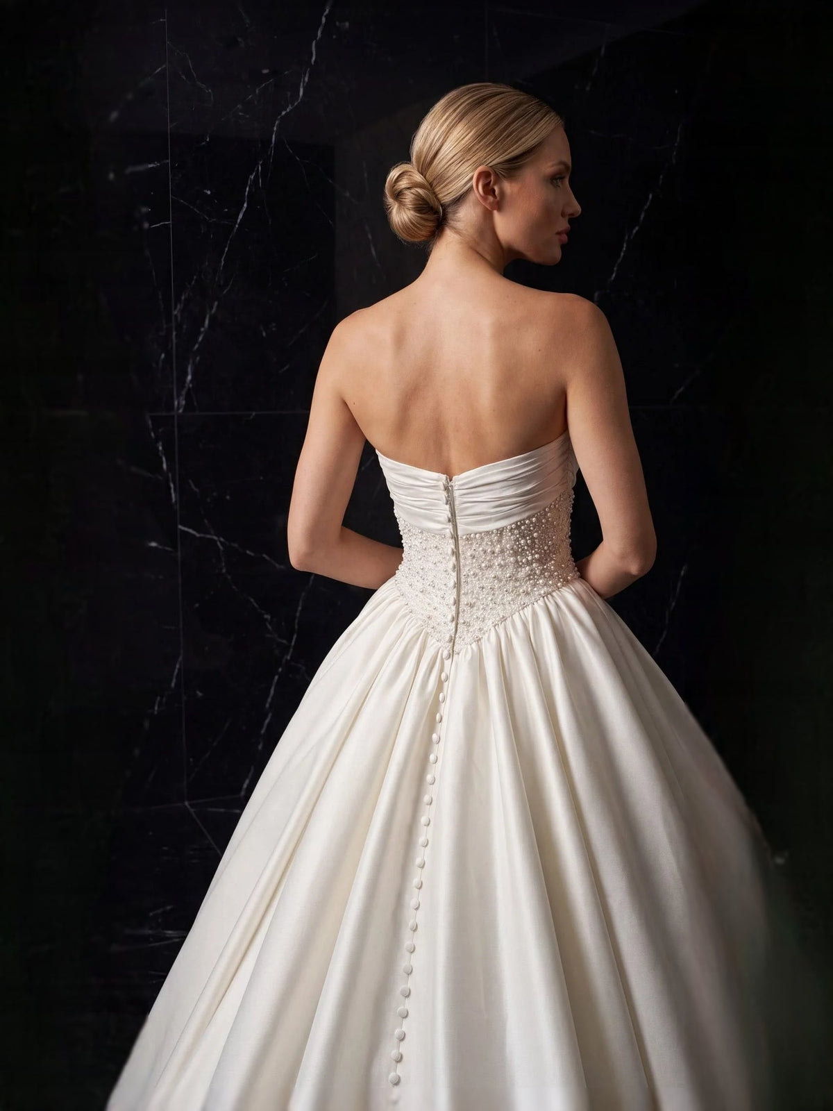 Ivory strapless satin wedding gown from back view with beaded panel and button details