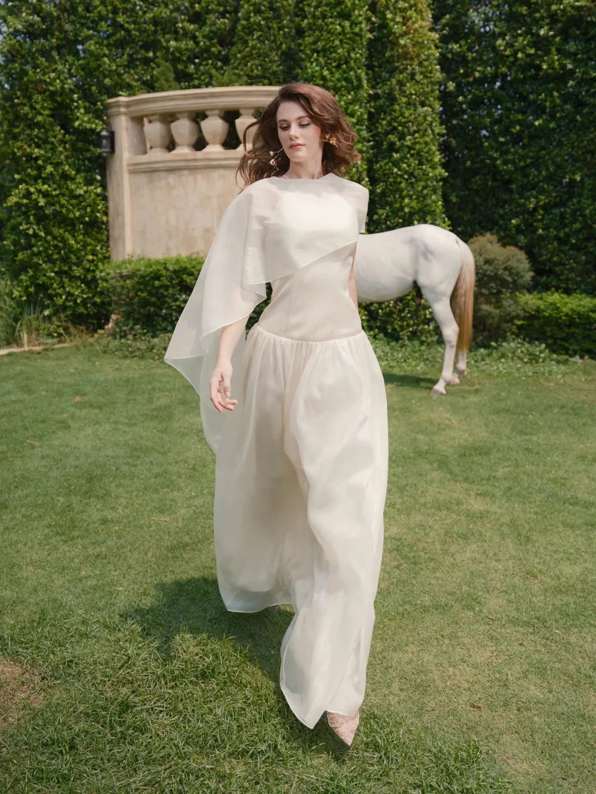 Ivory chiffon halter wedding dress with capelet sleeve drape and flowing floor-length skirt