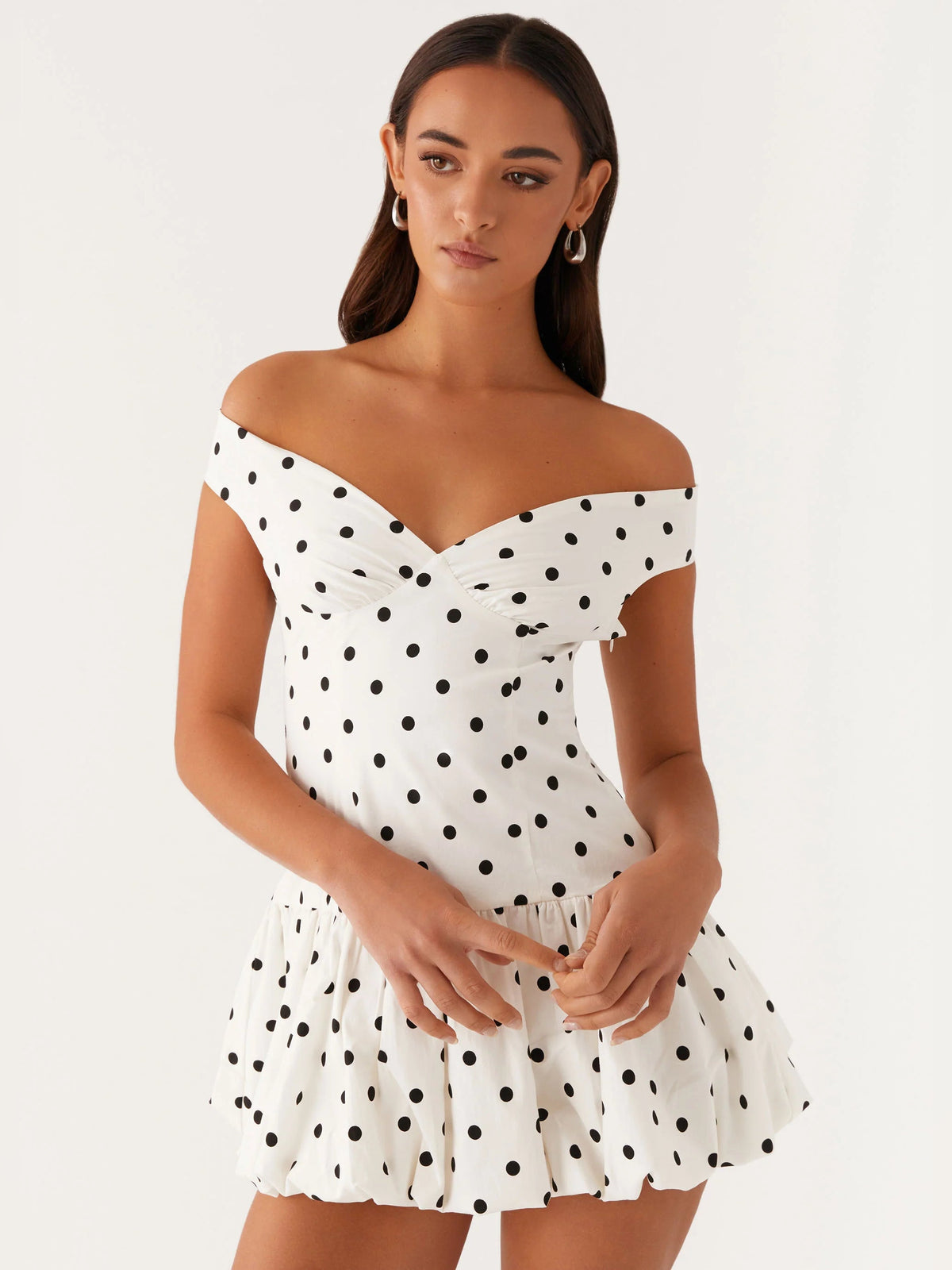 Off-shoulder mini dress close front view in white with black polka dots, gathered waist detail