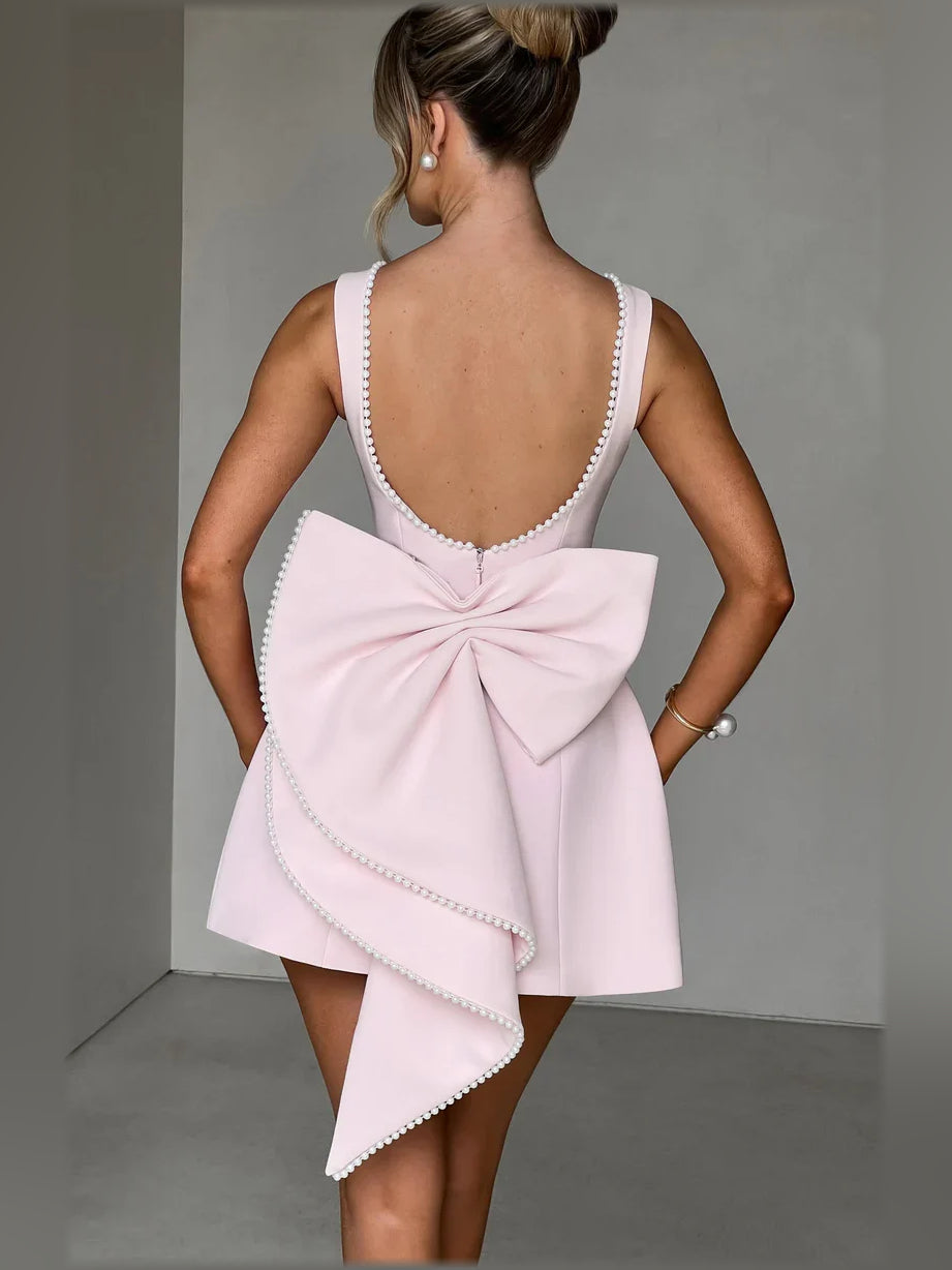 Blush open-back mini dress with V-back pearl trim and bow detail