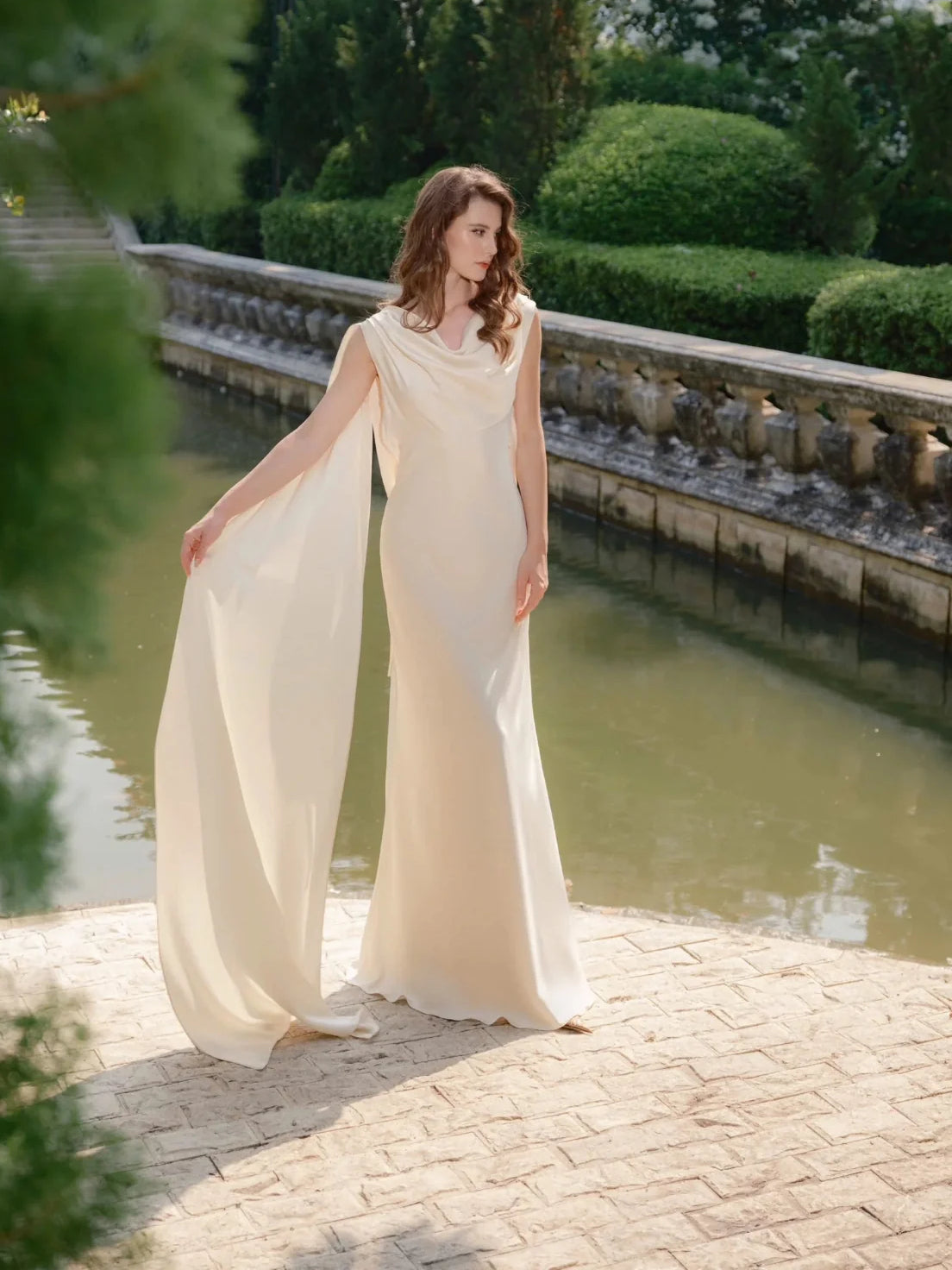 Ivory satin wedding dress with open back and flowing drape around the skirt