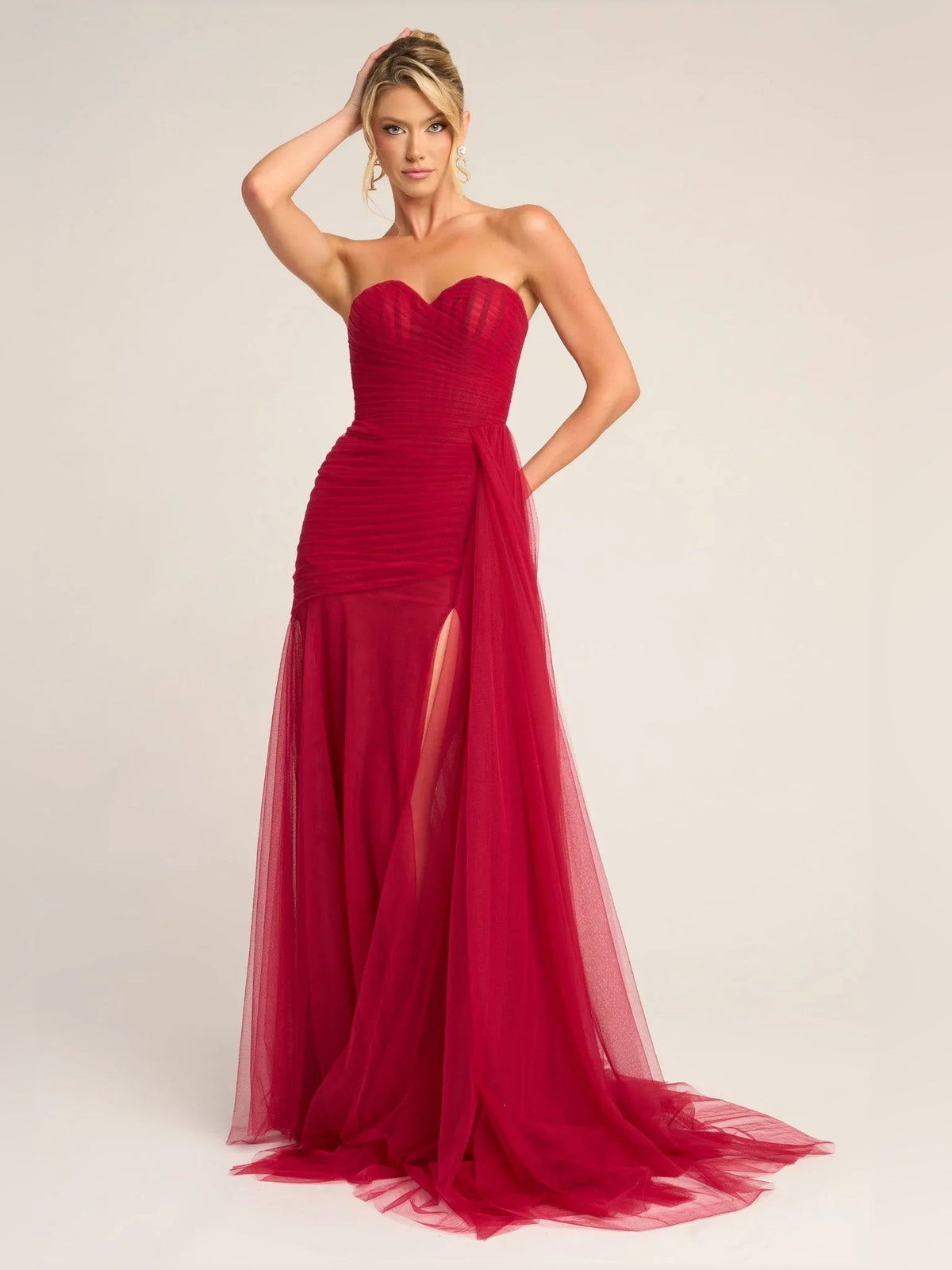 Red strapless sweetheart draped mermaid formal dress with sheer tulle skirt.