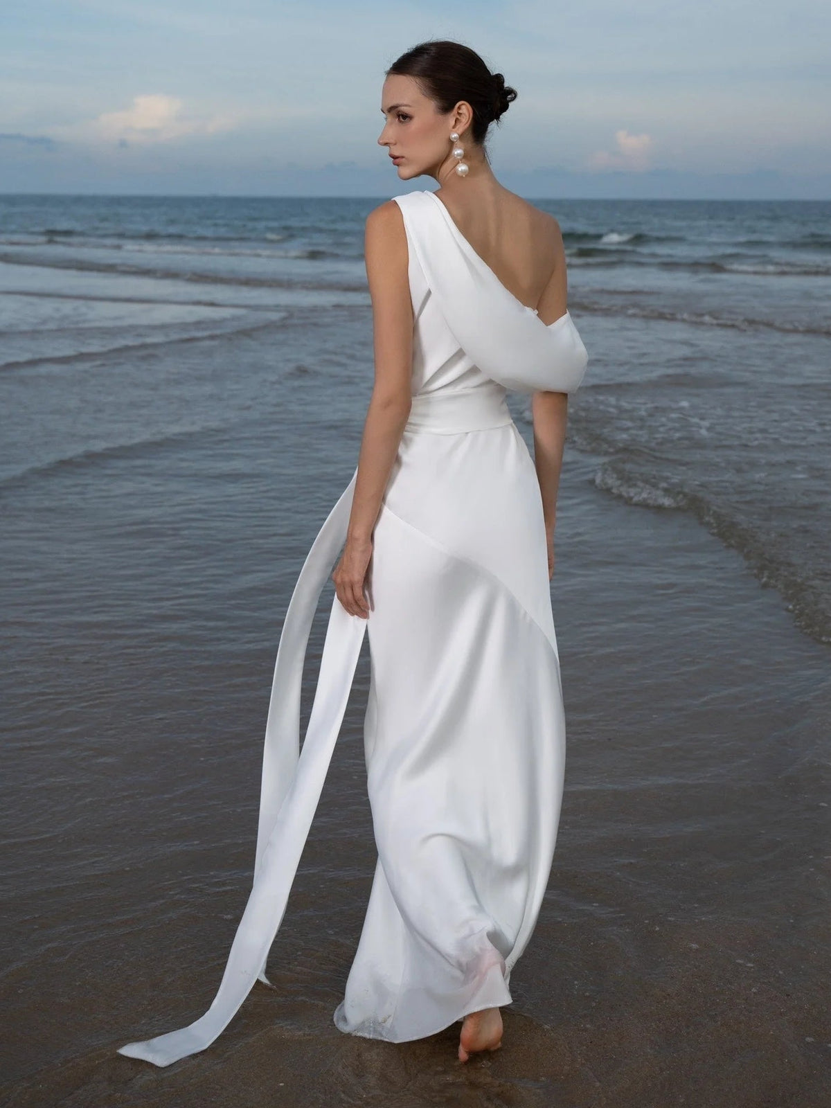 White satin sleeveless halter-neck sheath midi dress with long trailing drape panel
