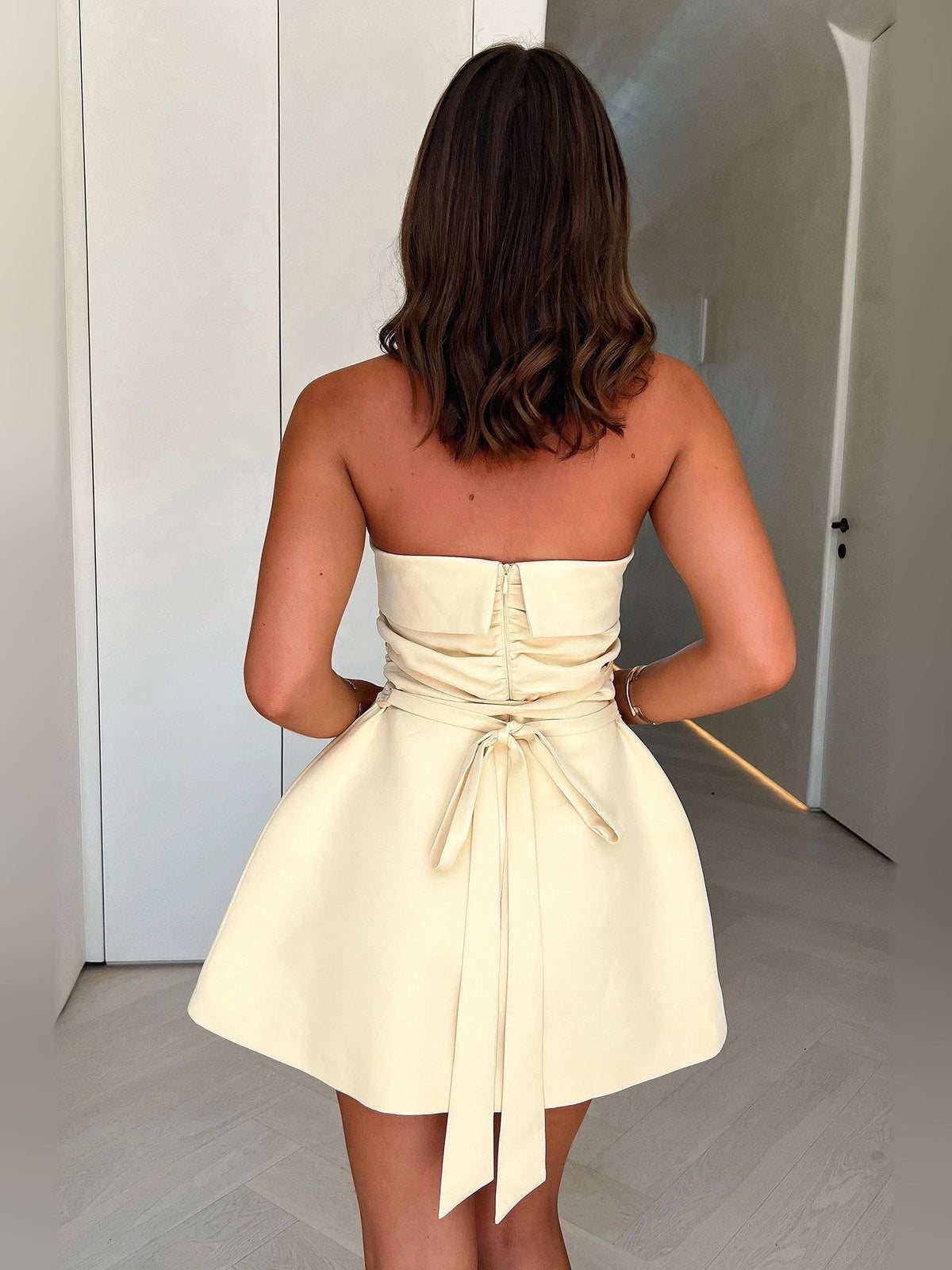 Back view pale lemon strapless A-line mini dress with lace-up waist tie