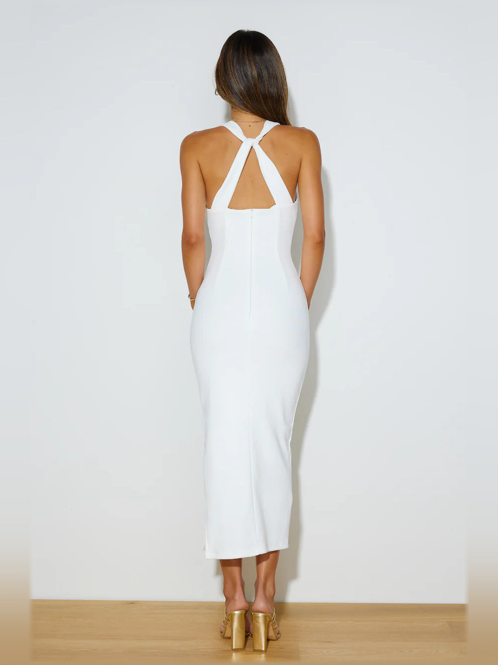White sleeveless midi dress with open back, crisscross straps, and fitted shape