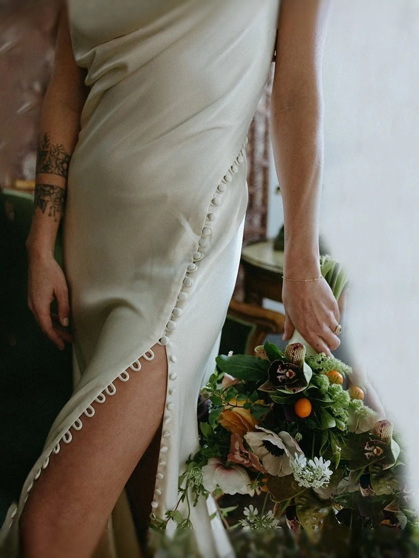 Ivory satin mermaid dress close-up: scalloped slit trim and draped corset detail