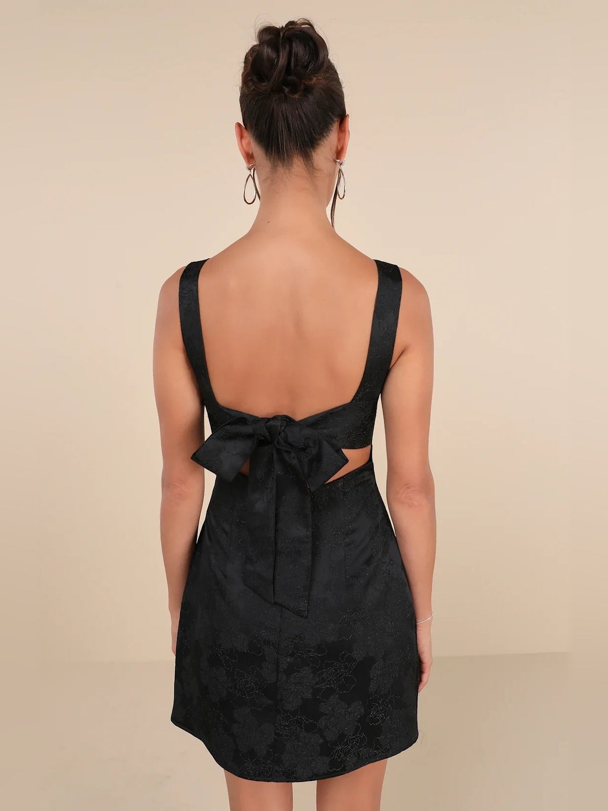 Black mini dress with open back cut-outs and bow detail at lower back