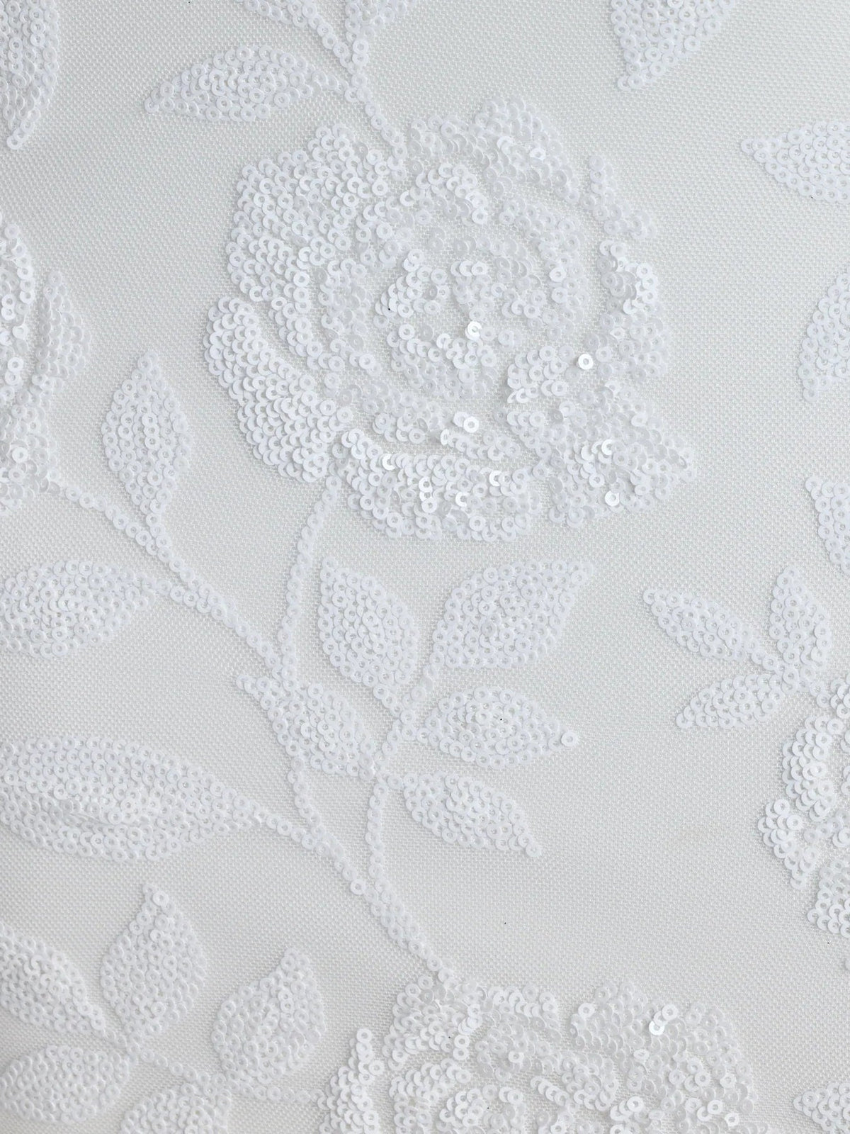 White sequin floral fabric close-up with leaf and flower pattern texture