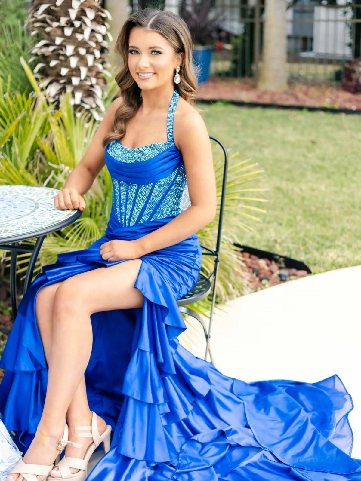 Cobalt blue halter prom dress with ruched corset bodice, ruffled skirt, and thigh slit