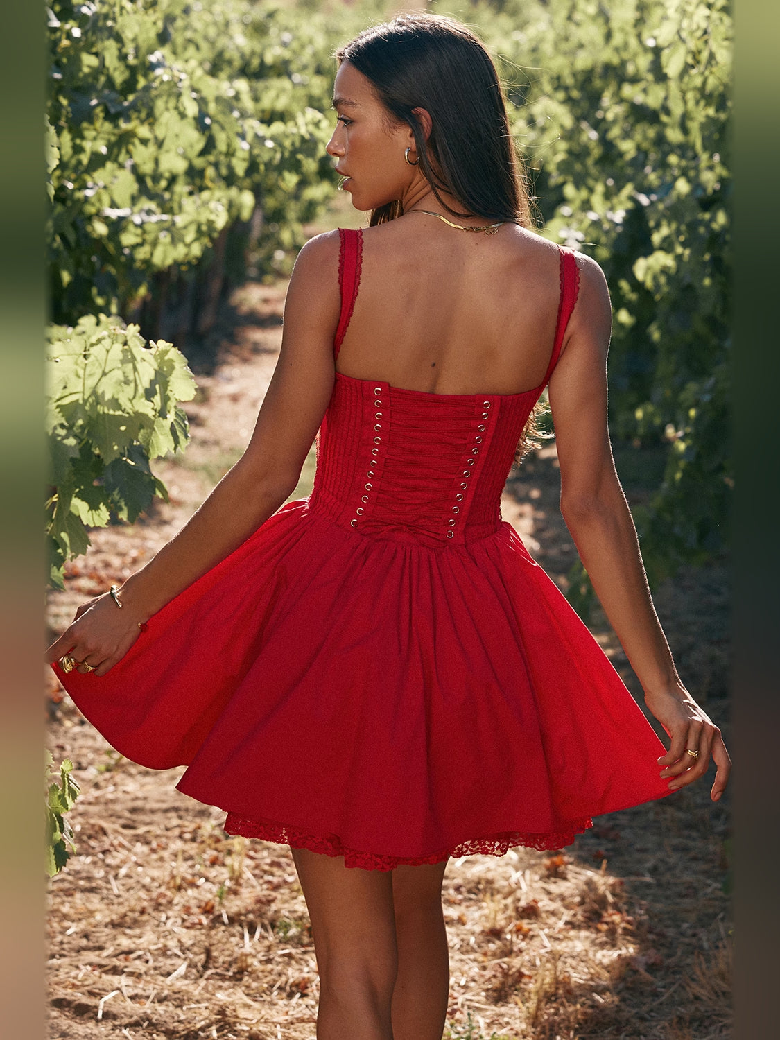 Back view of red corset mini dress with thin straps and ruched waist, tiered skirt