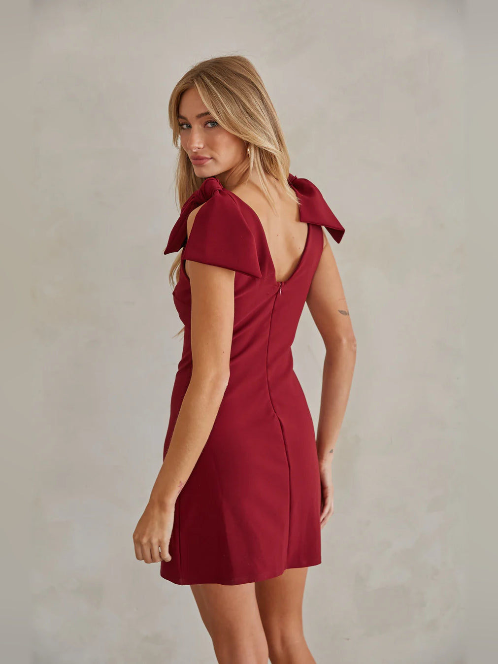 Red mini dress in side view with V-neck and bow cap sleeves