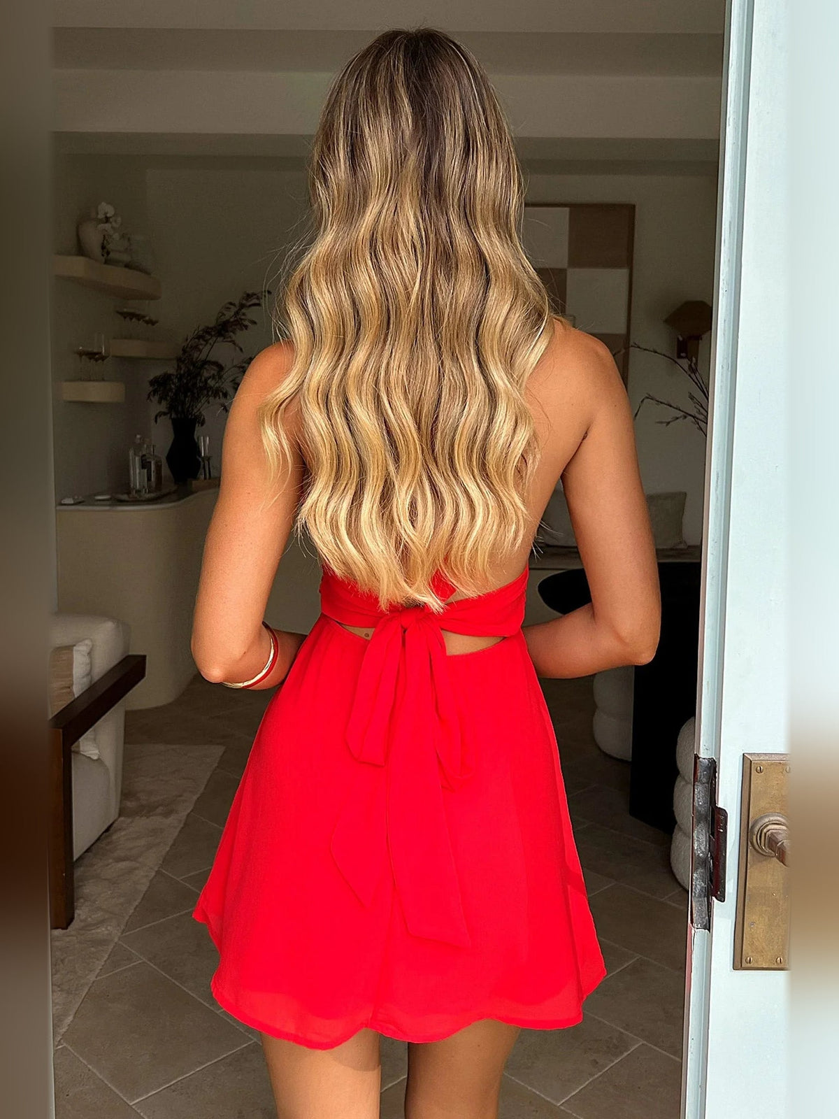 Red mini dress shown from the back with gathered waist and bow at center