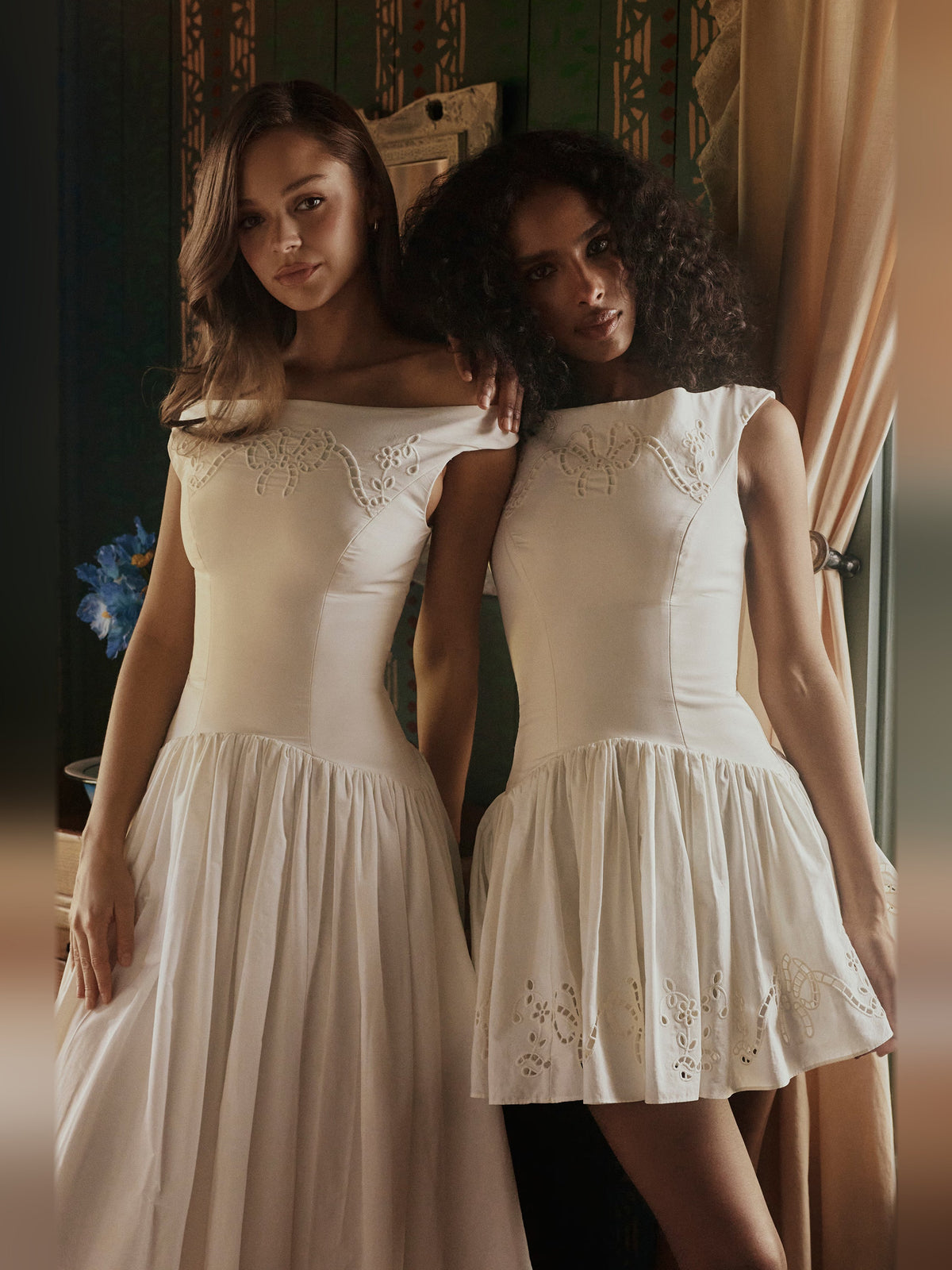 Two white boat-neck mini dresses side by side, sleeveless with embroidered bodice and hem