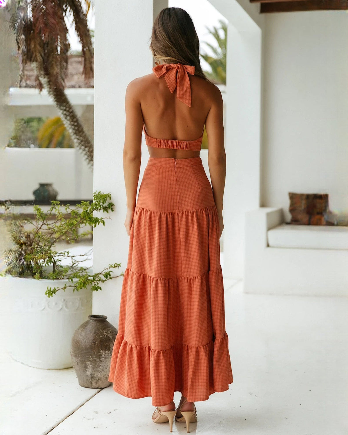 Back view of rust halter tiered maxi dress with bow at neck