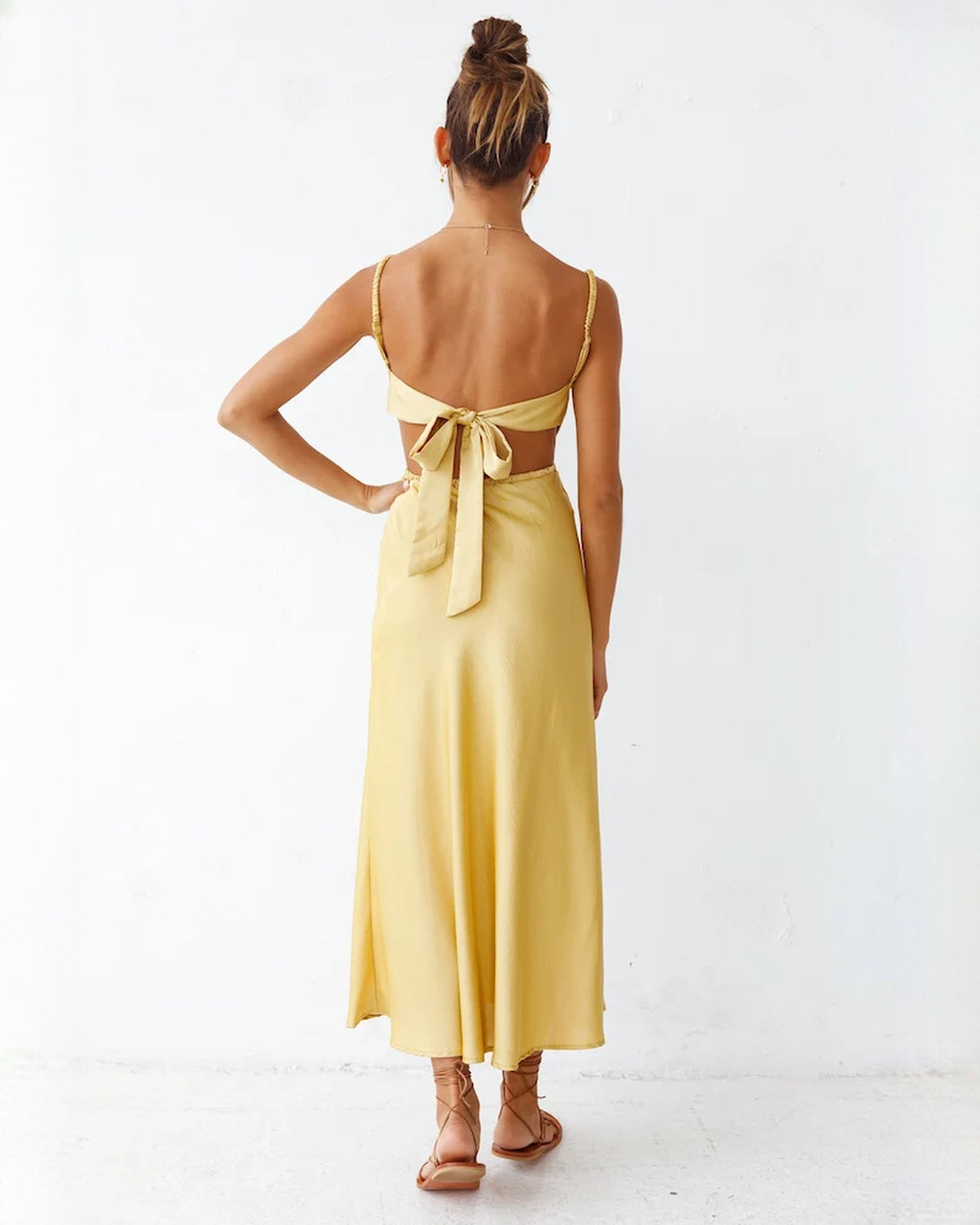 Back view of yellow satin sleeveless maxi dress with open back and tied bow