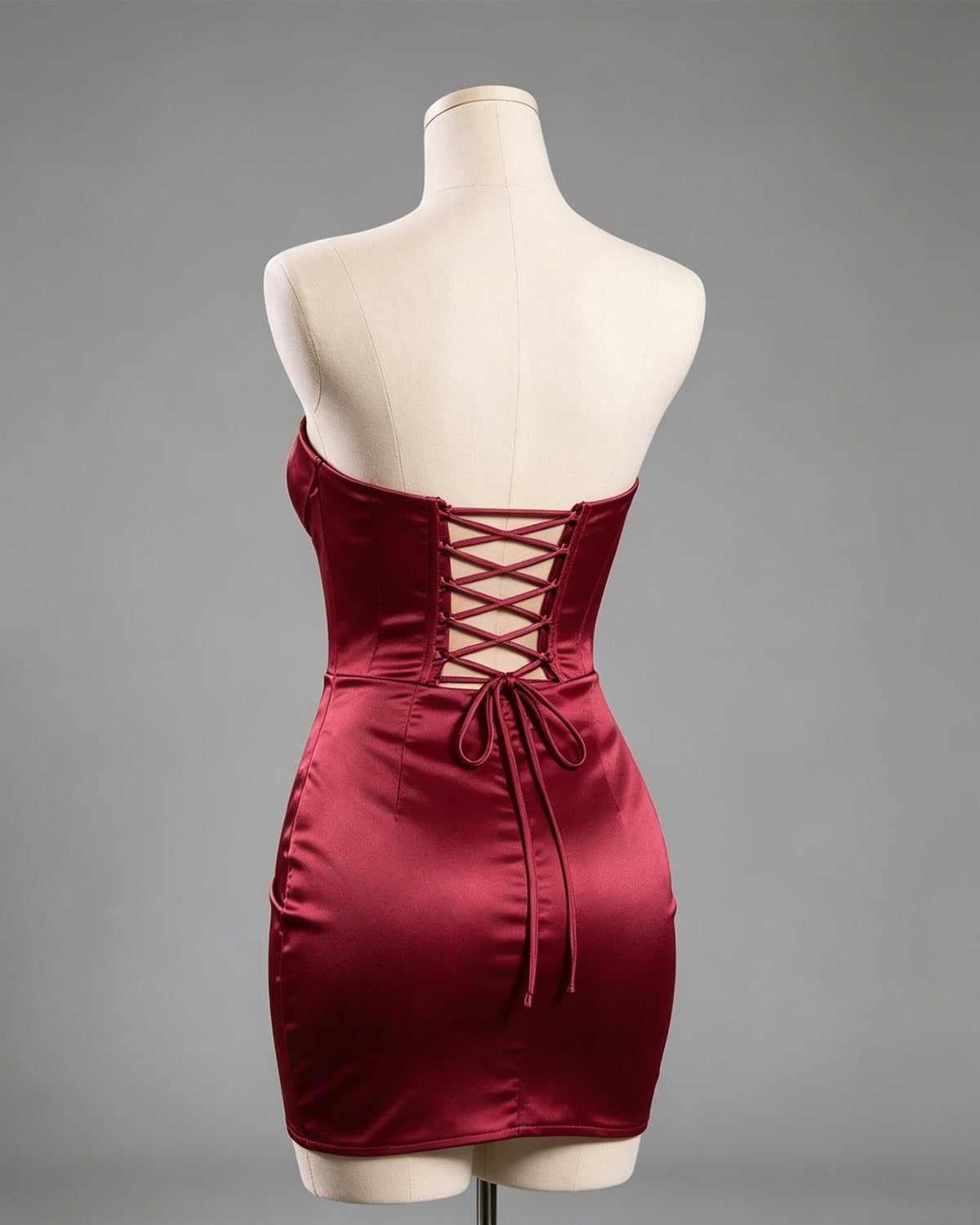 Burgundy satin mini dress on mannequin with lace-up corset back and wrap hem