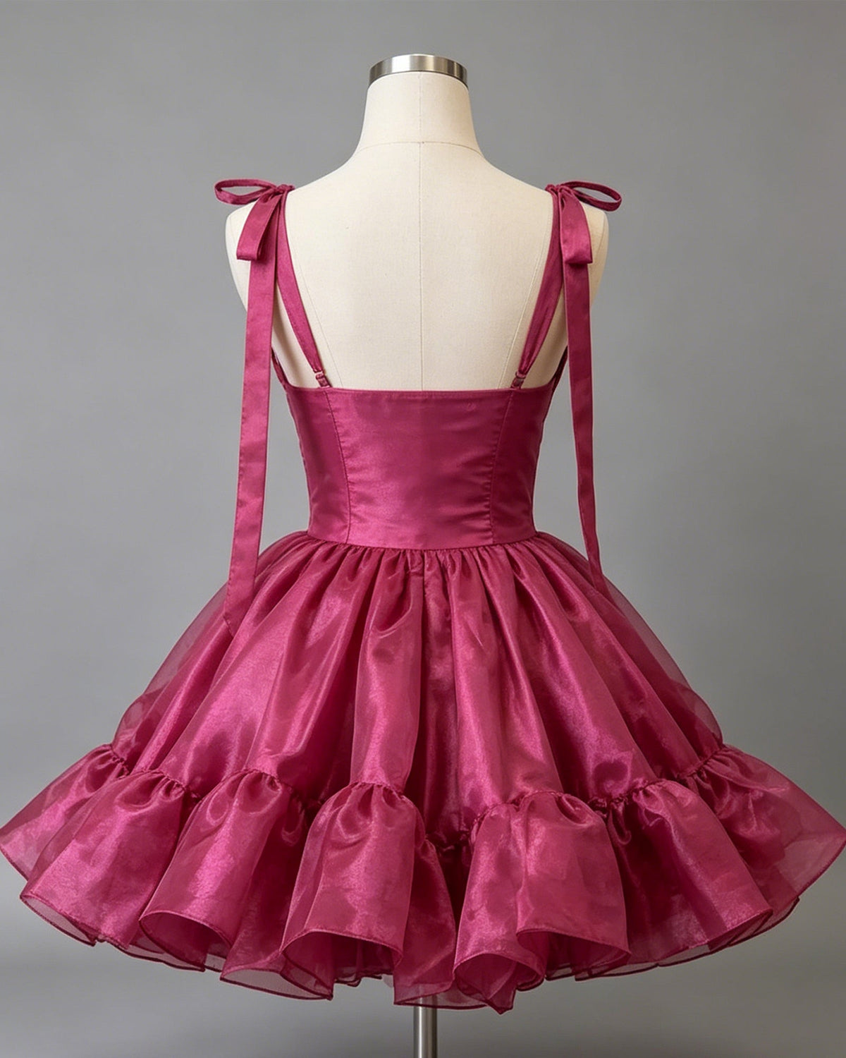 Magenta satin corset homecoming dress with open-back ribbon straps and tiered ruffles