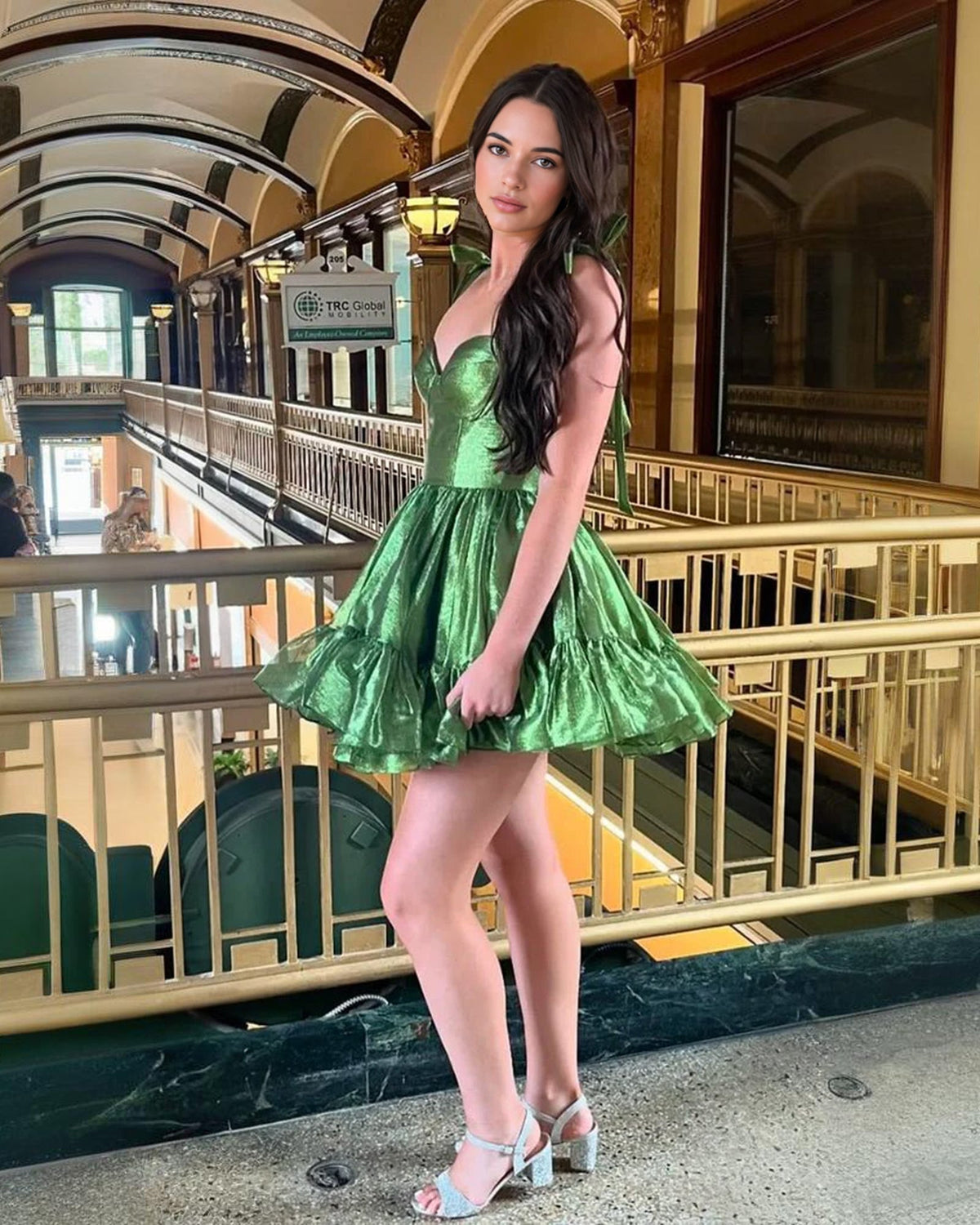 Emerald green satin corset homecoming dress with bow straps and flared ruffle skirt