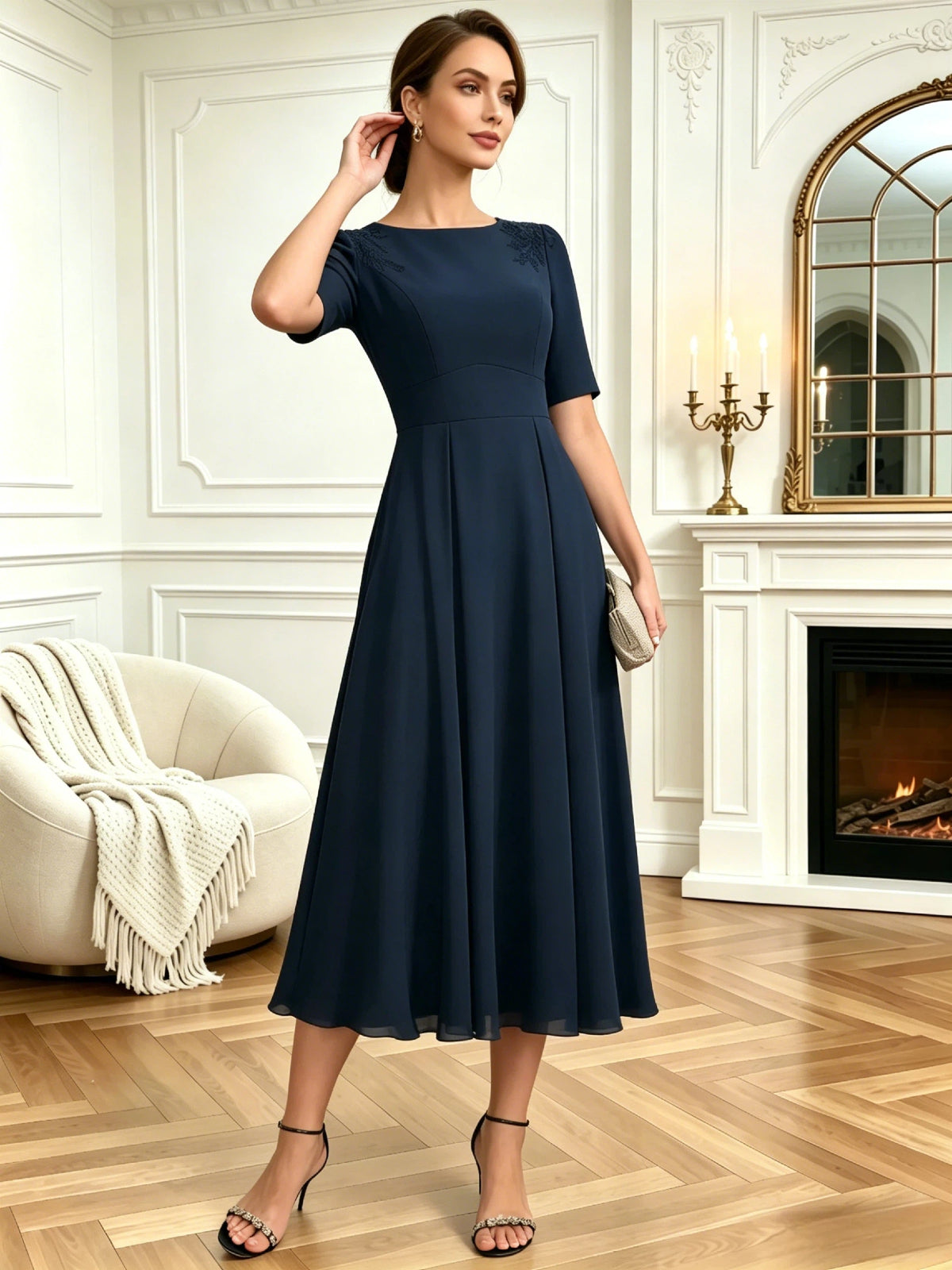 tea length mother of the bride dress with jewel neckline, short sleeves, A-line skirt, and shoulder embroidery shown in a formal wedding guest setting