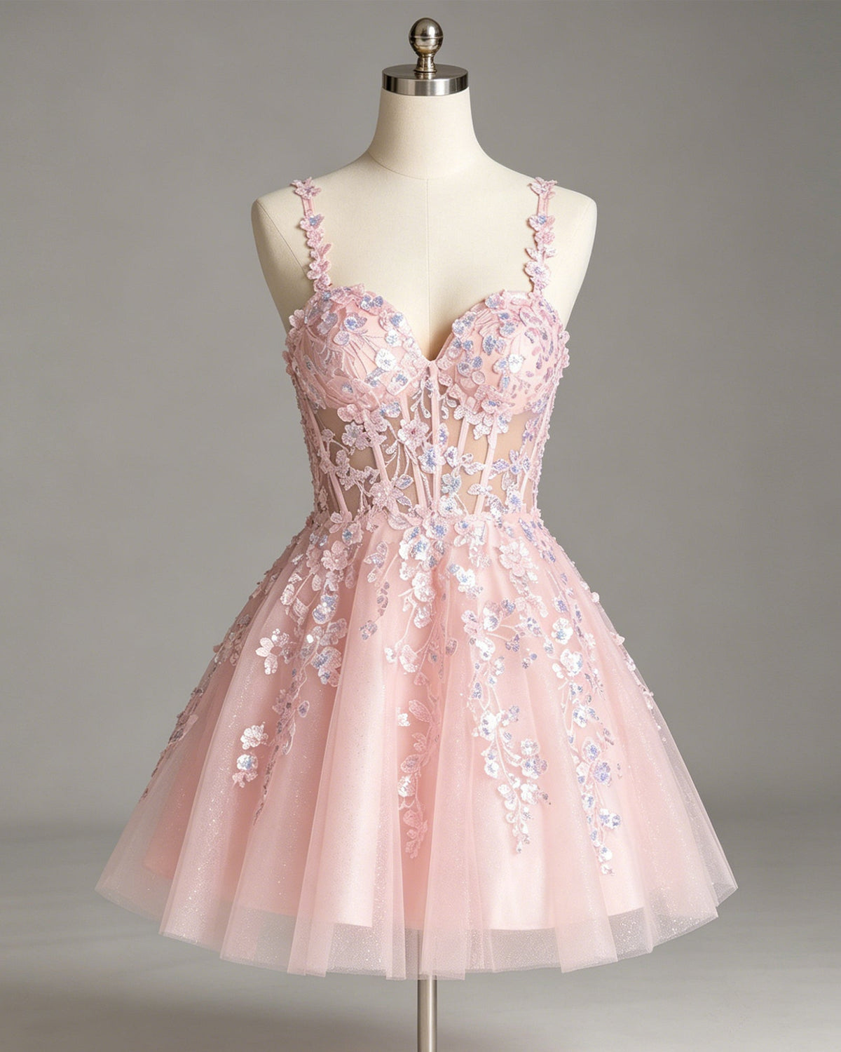 Pink tulle corset homecoming dress on mannequin with floral glitter applique bodice