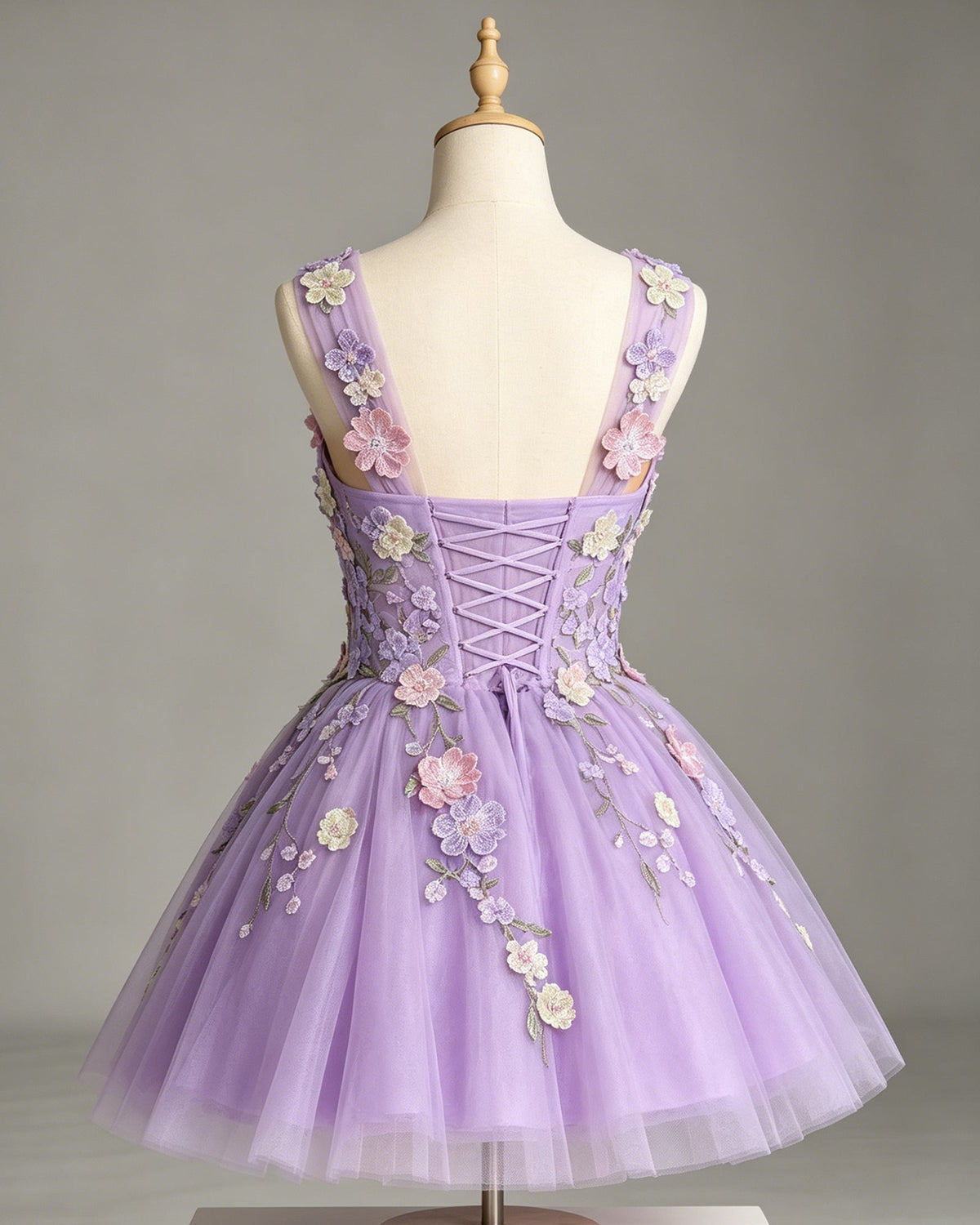 Lavender tulle A-line dress on mannequin with floral appliques and corset-style lace back