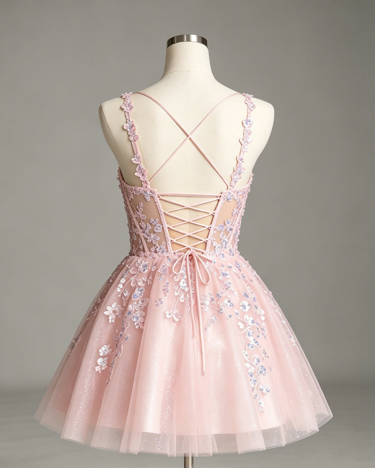 Pink tulle corset homecoming dress on mannequin back with crisscross lace-up straps