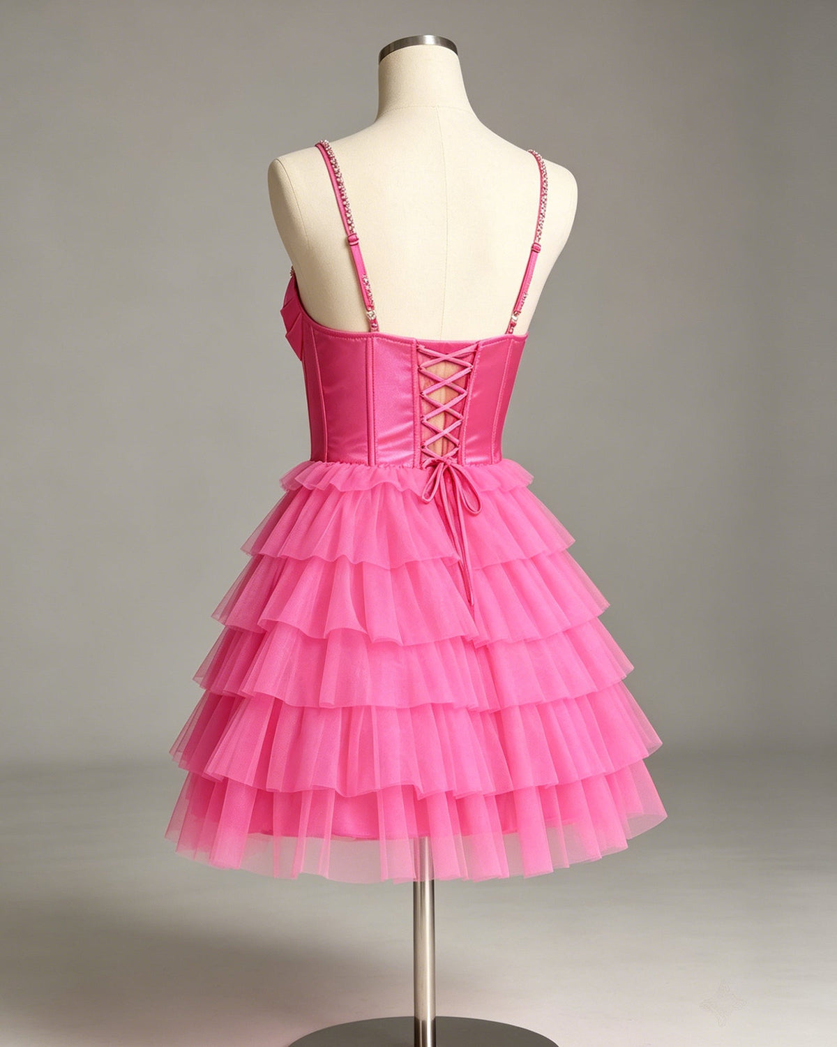 Pink beaded corset dress on mannequin with strappy back and tiered tulle skirt