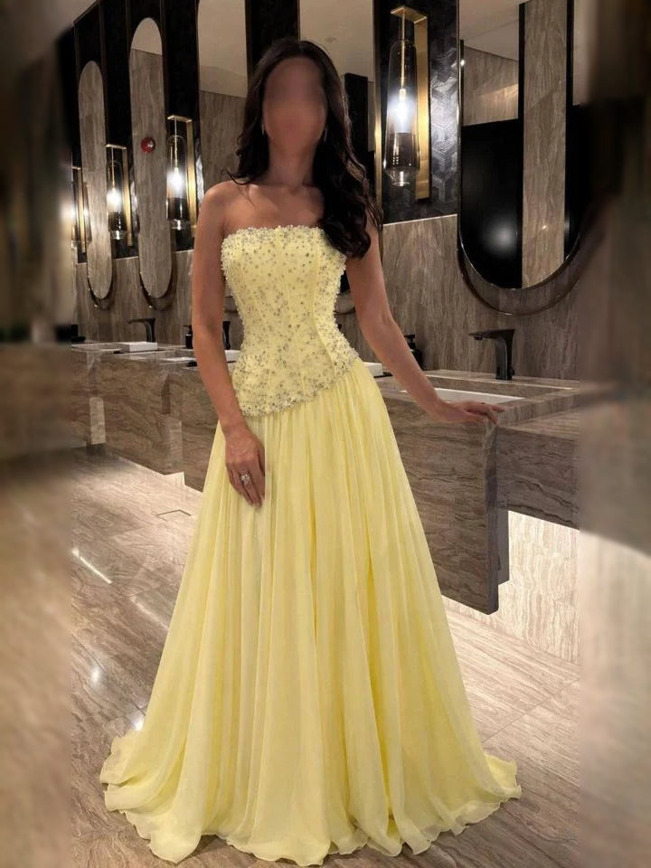 Pale yellow strapless corset formal dress with floral beaded bodice, flowing full skirt