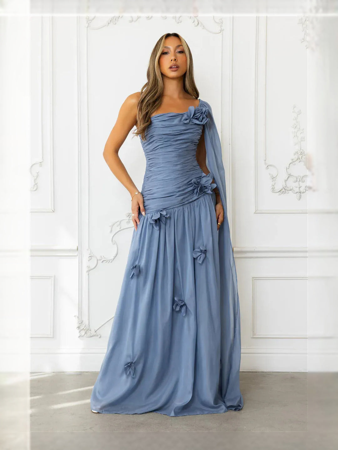 Dusty blue ruched one-shoulder maxi dress with bow-trim skirt and draped shoulder overlay
