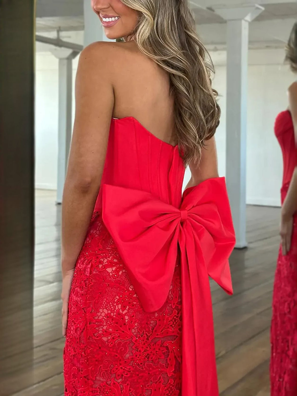 Red strapless mermaid prom dress with corset bodice and oversized back bow, lace overlay