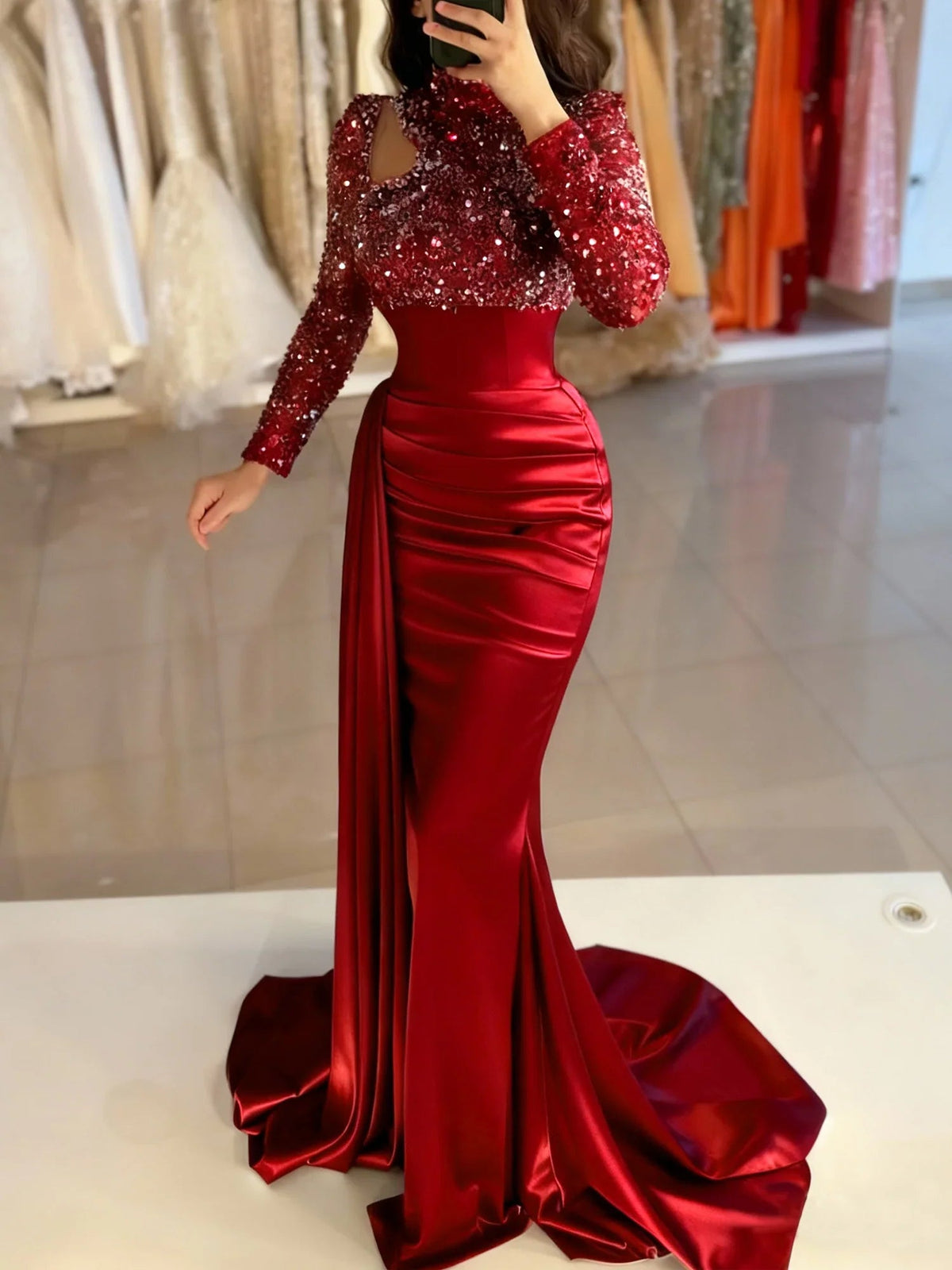 Red satin mermaid dress with sparkling sleeves, fitted waist, and front slit