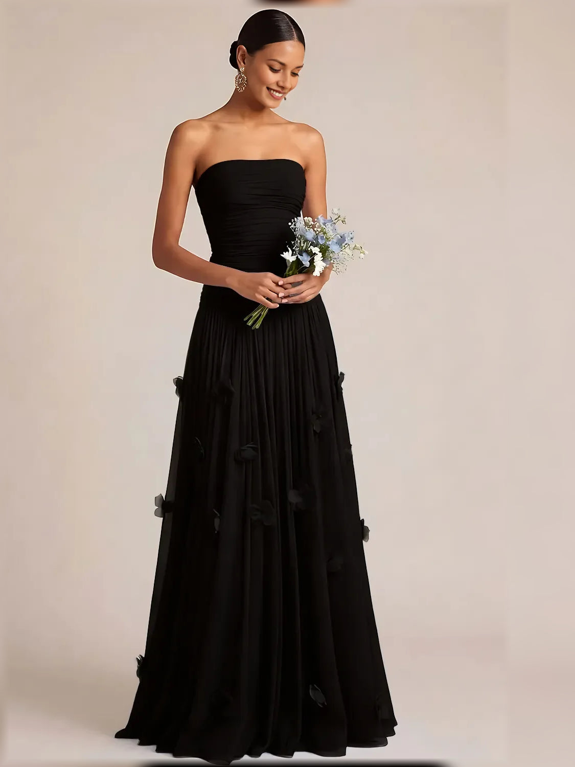 Black strapless ruched formal dress with floor-length pleated skirt and floral appliques