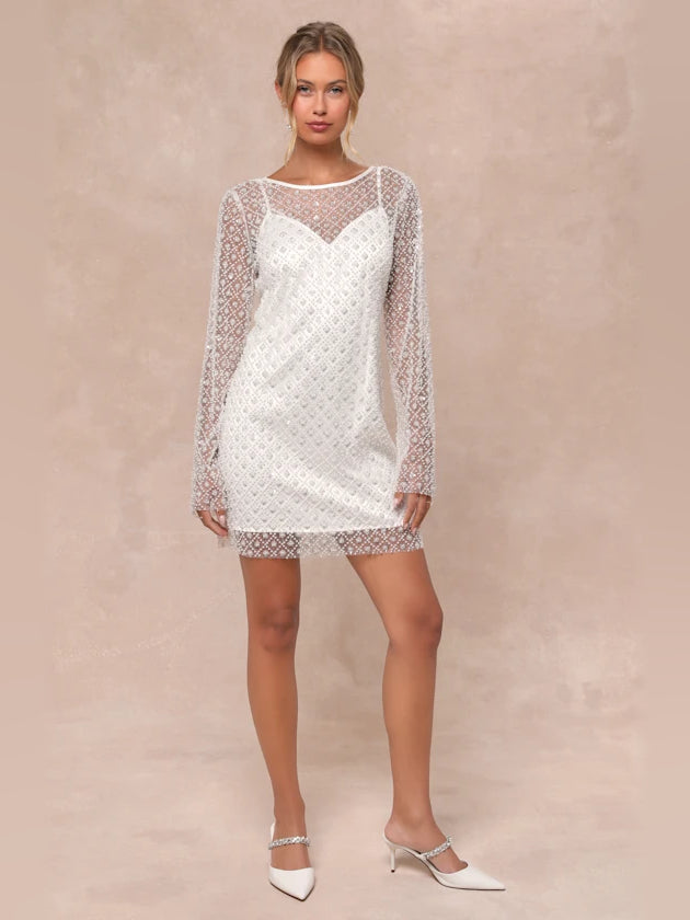 White sequin mini homecoming dress with sheer sleeves and short shift silhouette.