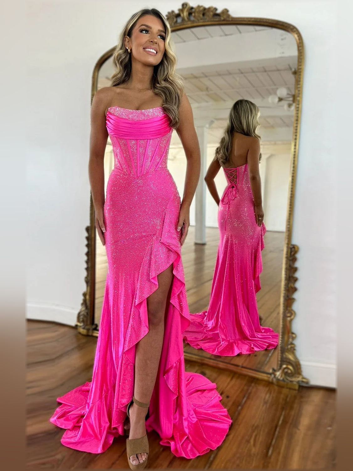 Hot pink strapless mermaid formal dress with sparkling fabric and front slit detail.