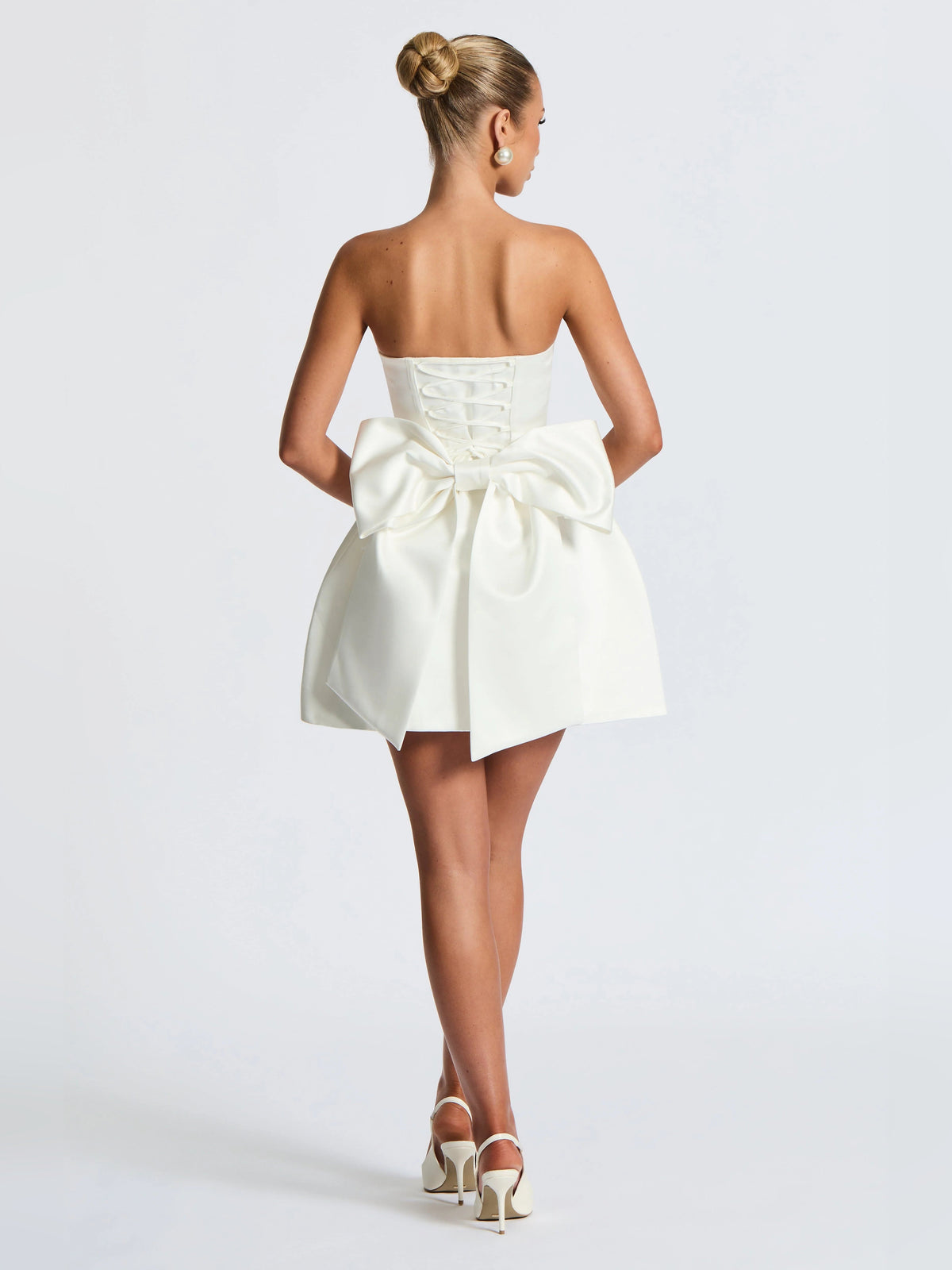 Ivory mini strapless dress with lace-up back bodice and tied waist bow, back view.