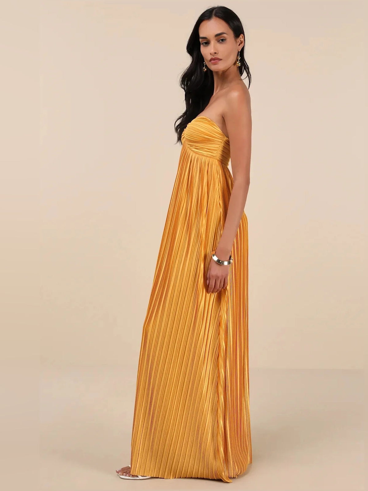 Gold satin strapless bridesmaid dress with ruched sweetheart bodice and pleated maxi skirt