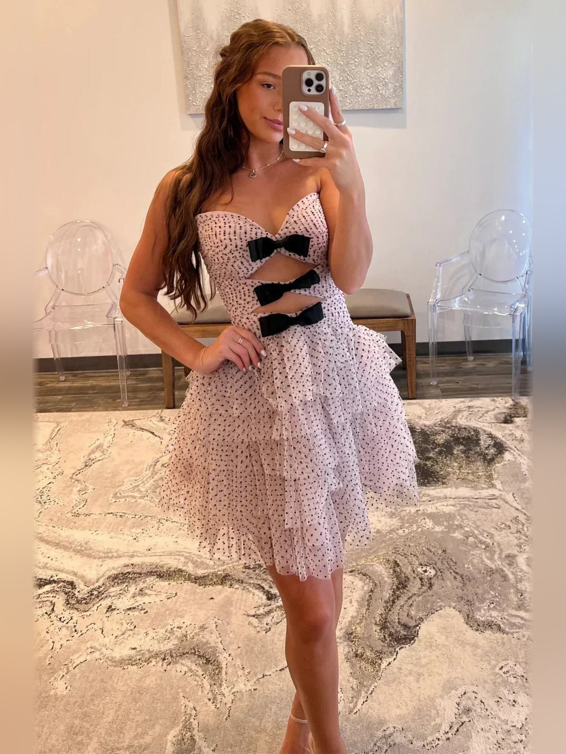 Pink mini tulle dress with sweetheart neckline, black bow cutouts, and flared tiers