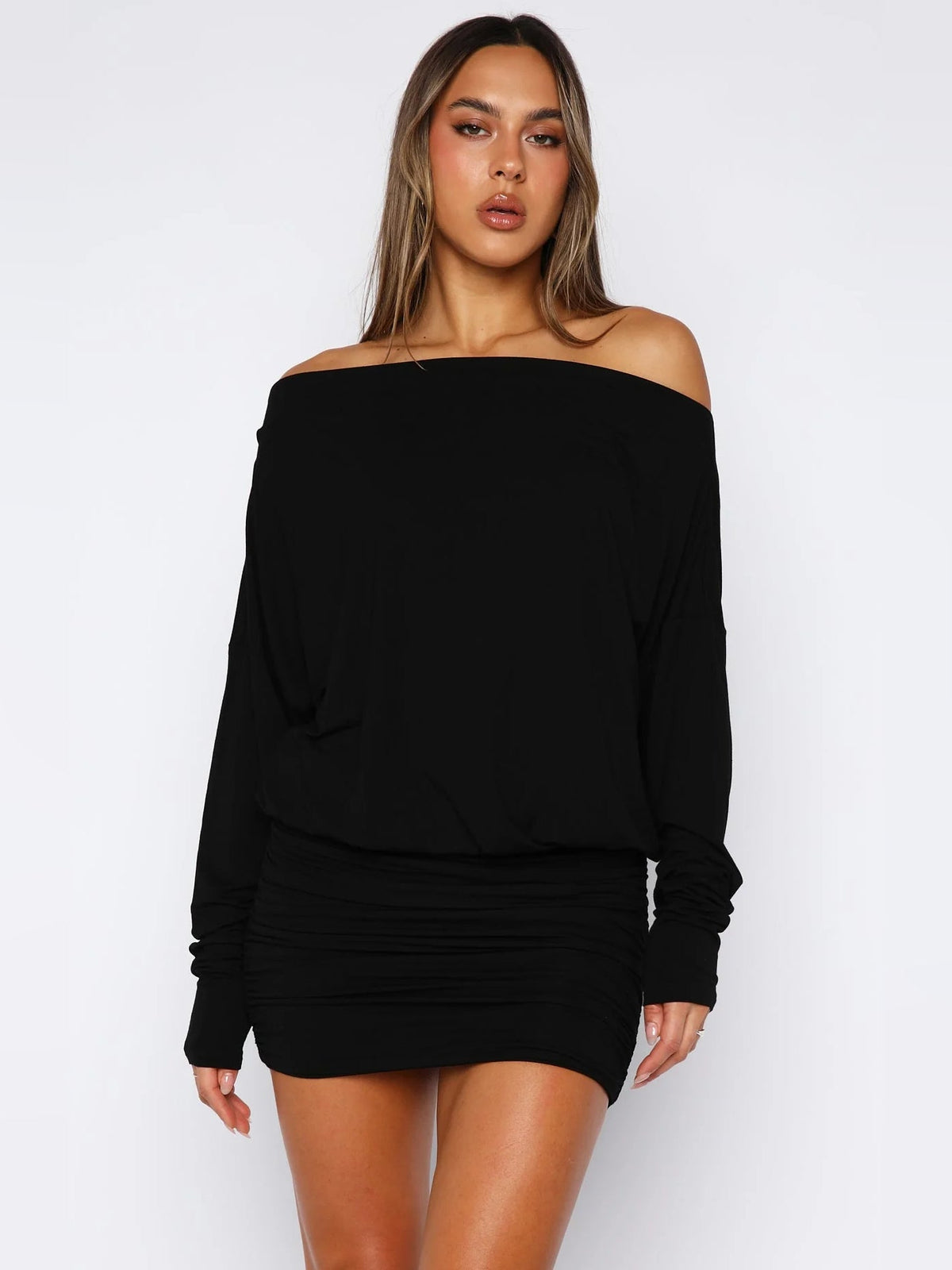 Black off-shoulder long-sleeve mini dress with draped top and ruched waist.